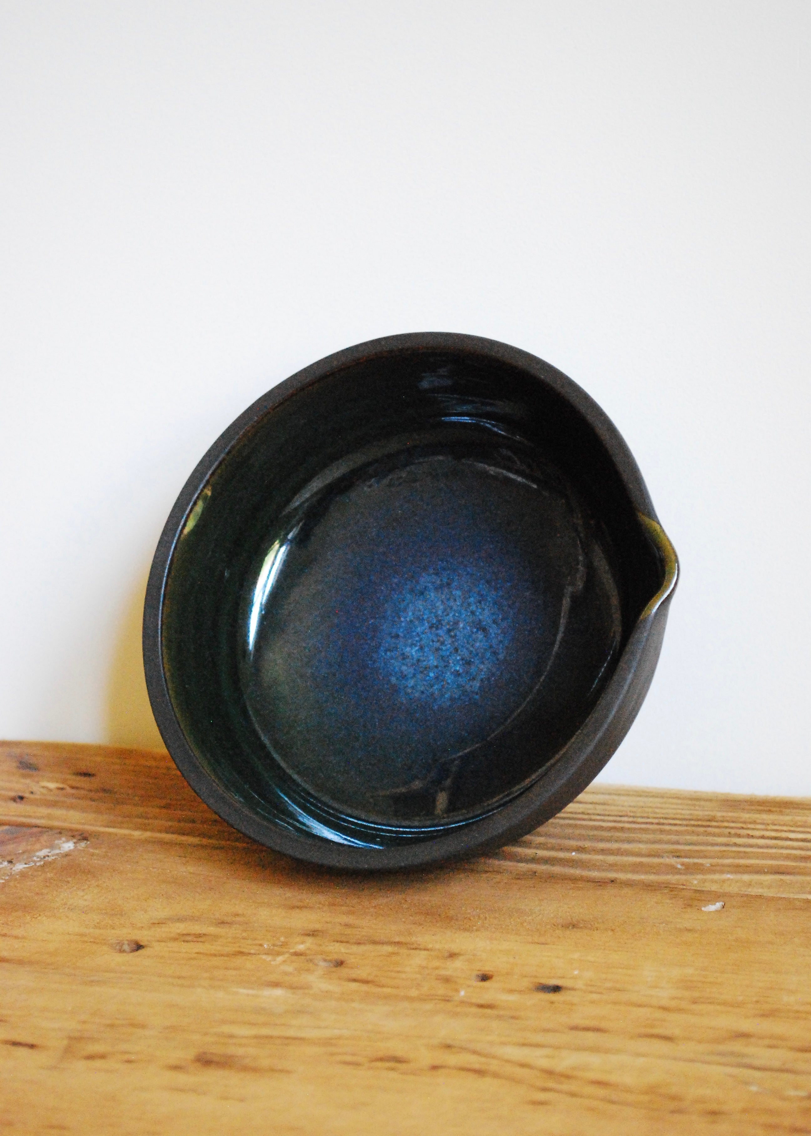 Handmade ceramic matcha bowl made in a black clay with blue and green interior glaze