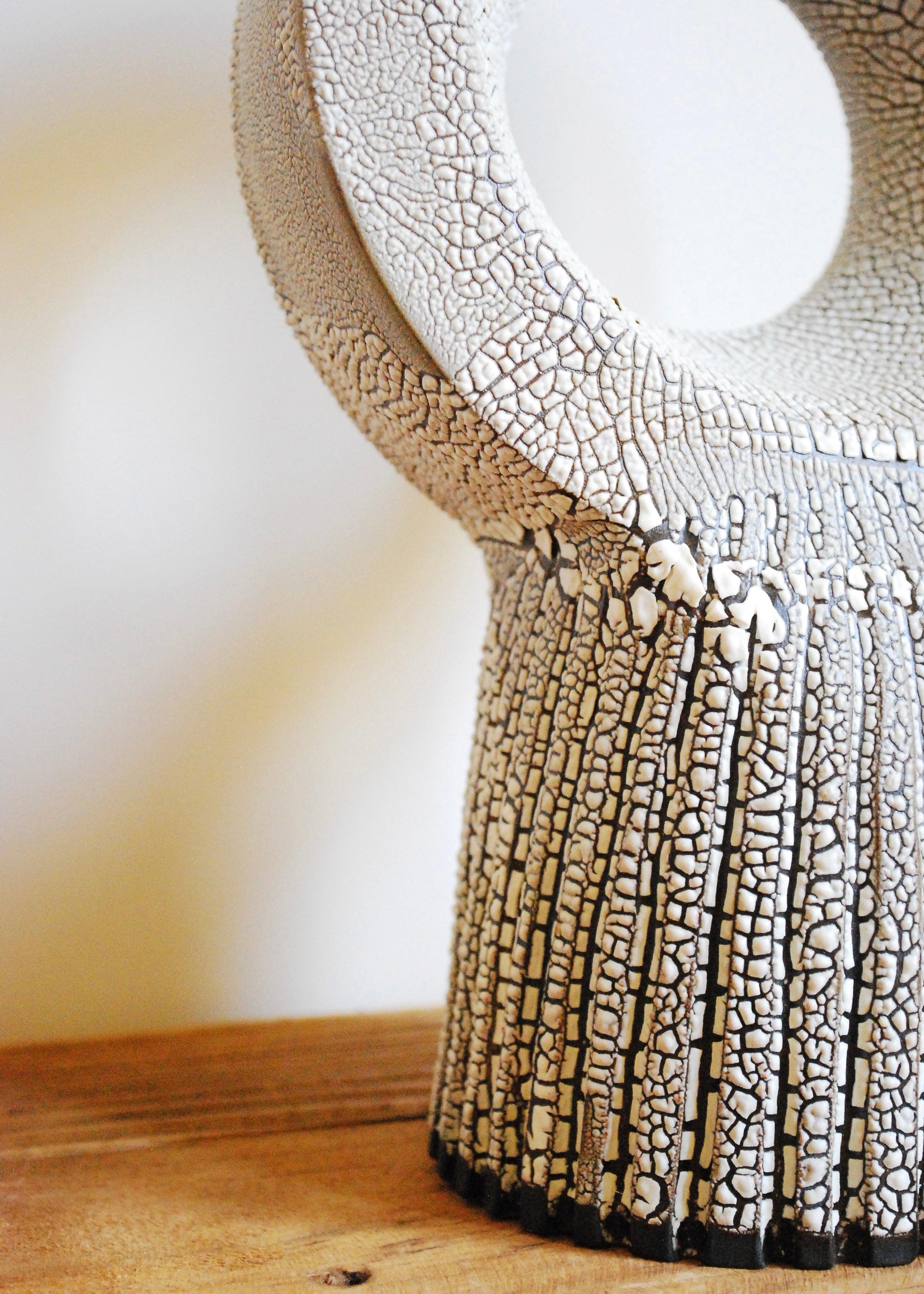 A handmade circular ceramic object with textural cracked white glaze