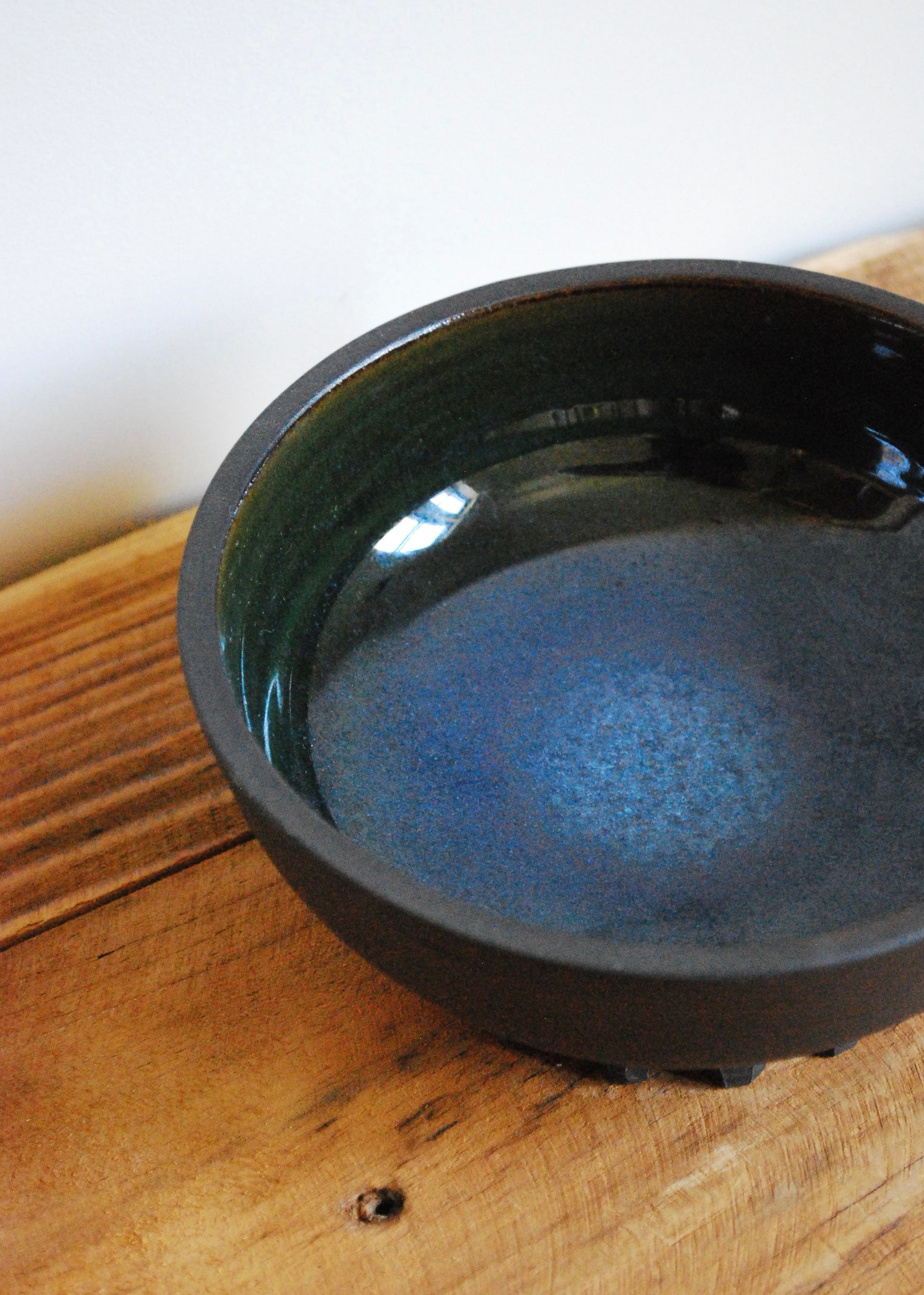 Handmade ceramic matcha bowl made in a black clay with blue and green interior glaze  